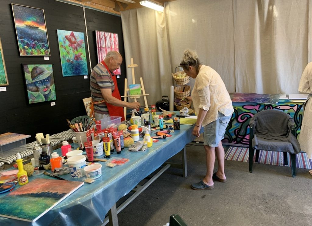 Deltagare i kreativ konstkurs målar på sina konstverk